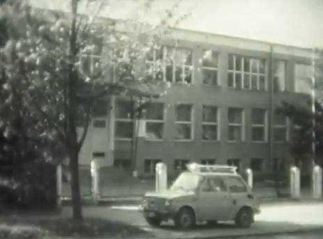Maluszek przed budynkiem szkoły